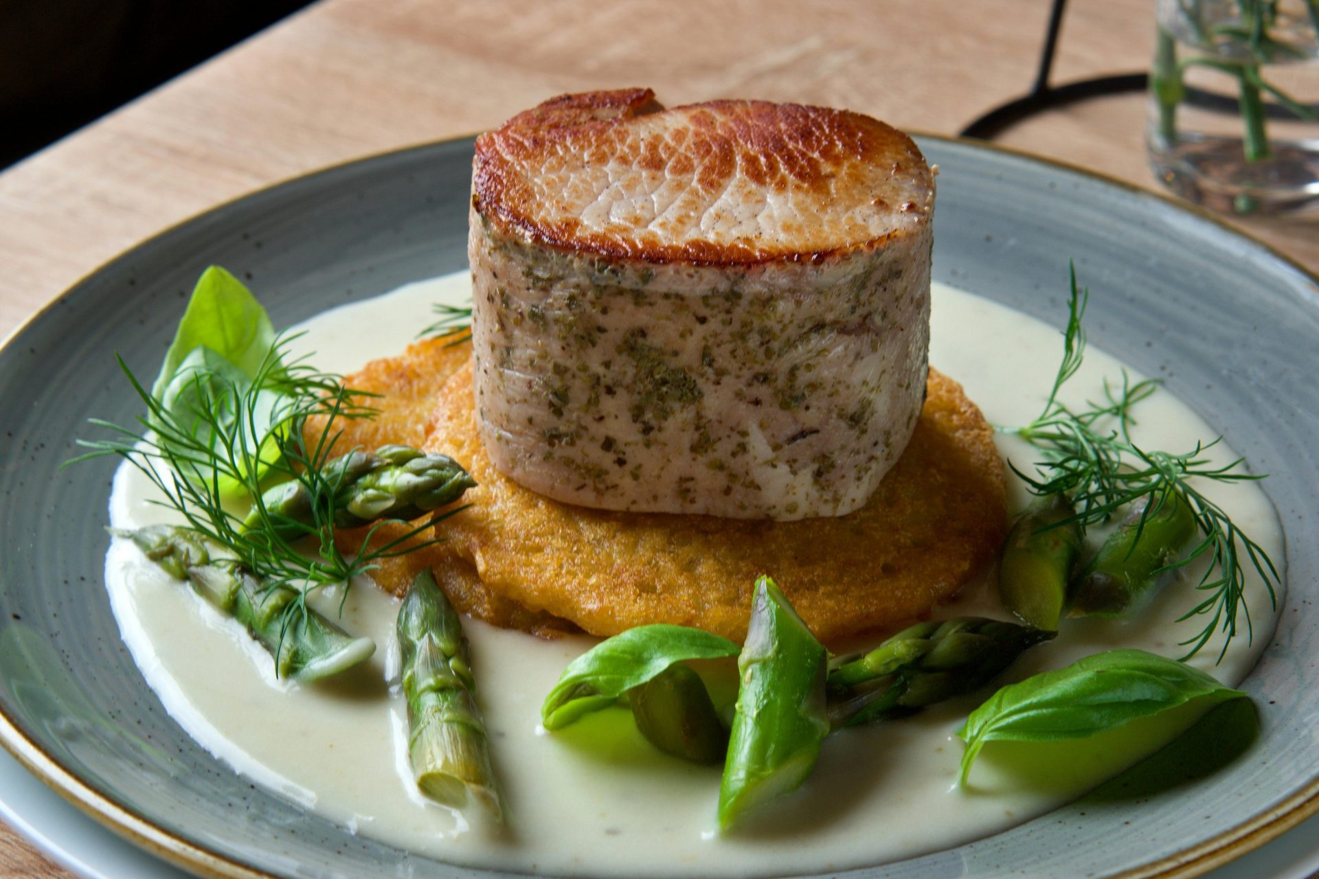 Delicious pork dish with asparagus, fresh greens, and creamy herb sauce.